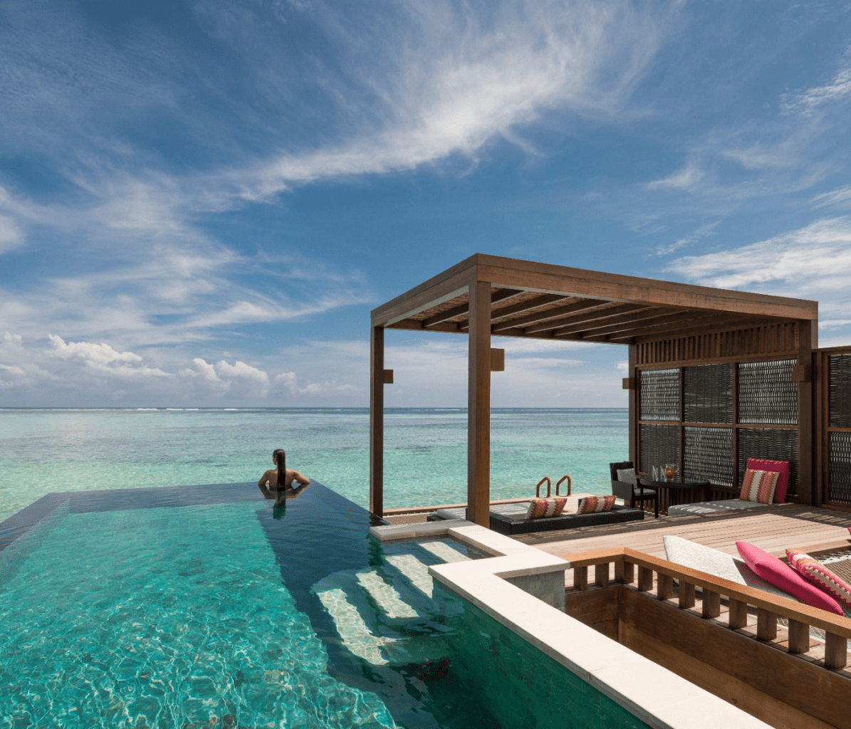 Four Seasons Resort Maldives at Kuda Huraa Woman Looking Our from Overwater Villa Best Hotels in Maldives 2023
