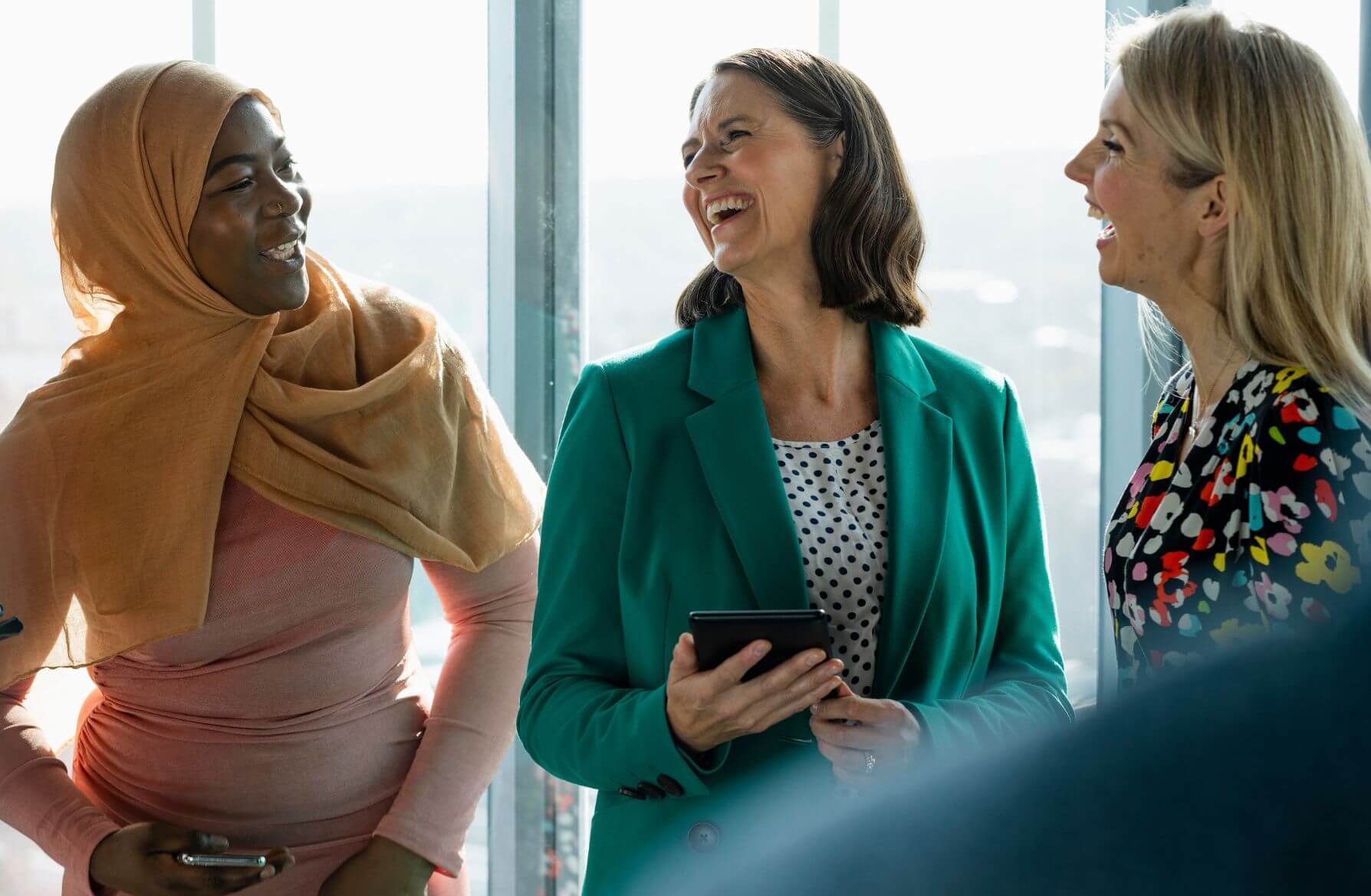 Business Women Laughing Together in Office at Work - Jobs Women Earn Higher Than Men