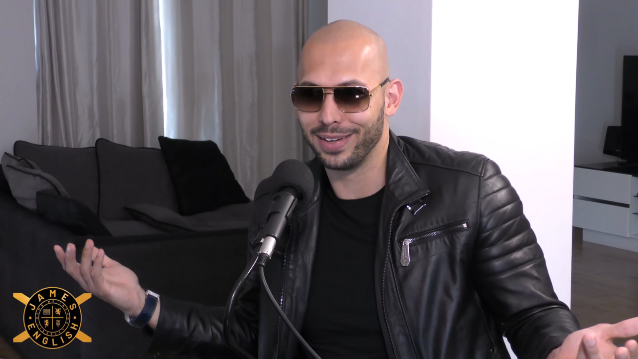 Andrew Tate sat talking in a black top and jacket with sunglasses on the Anything Goes With James English Podcast in 2021.