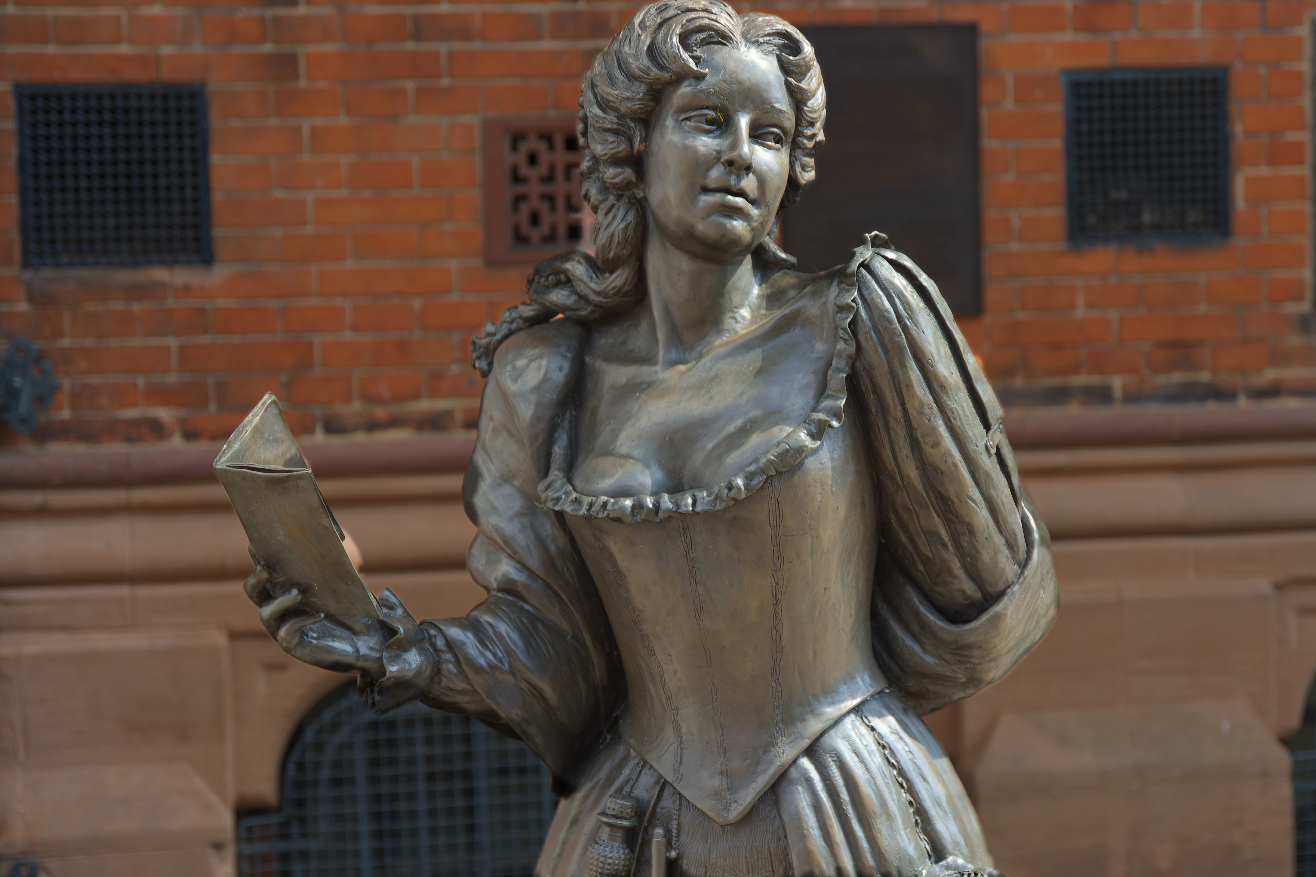 Photo of a statue of writer and spy Aphra Behn holding a book in one hand