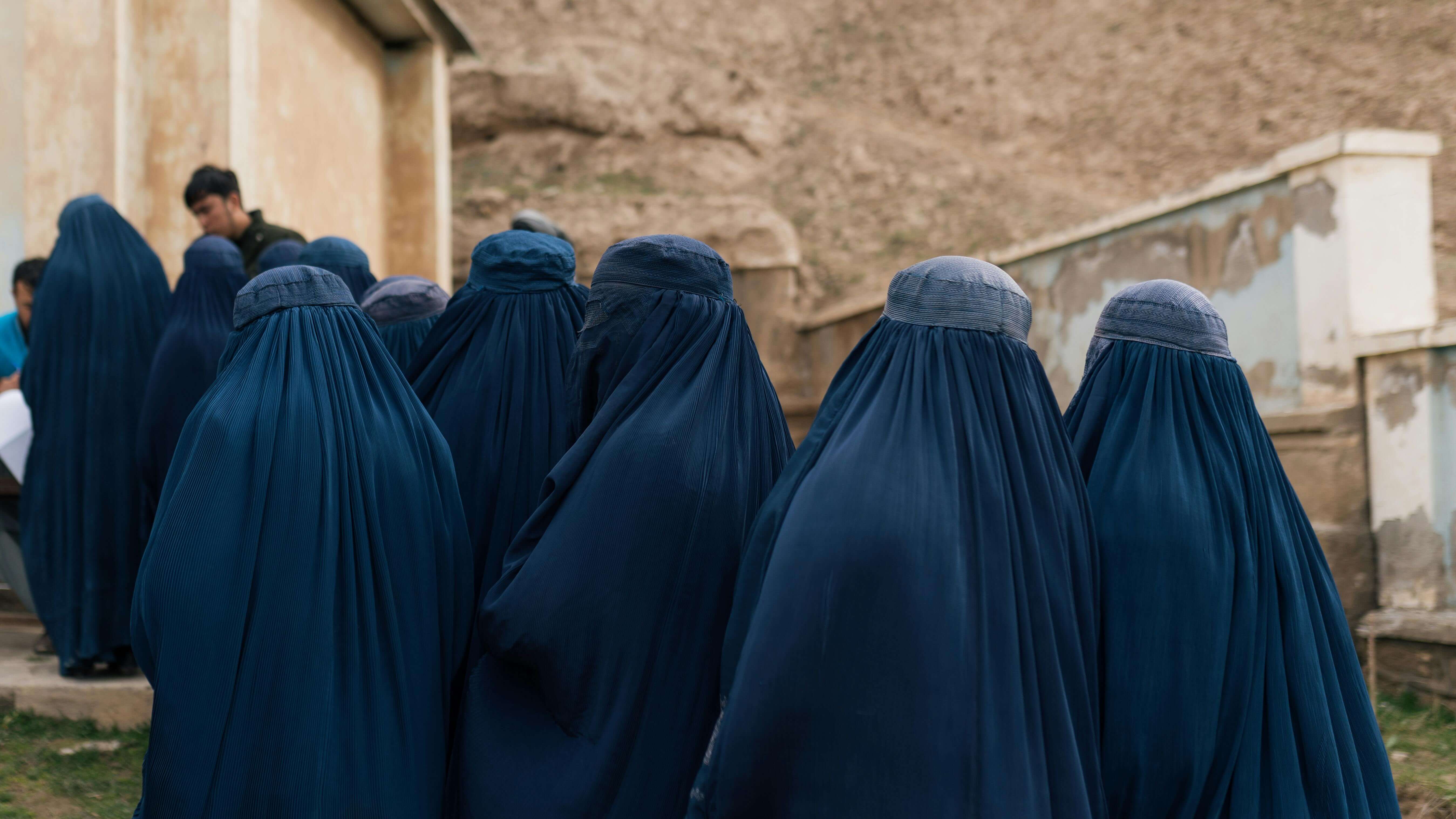 Afghan women in blue burqas gather outside a building amid women's rights threat under taliban rule as Afghanistan legalise domestic abuse and violence