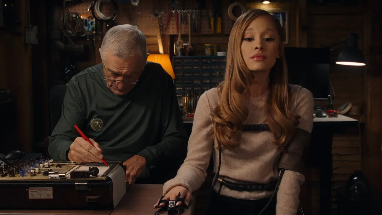 Ariana Grande's character Olivia Jones sits connected to a lie detector machine while Robert De Niro's Jack Byrnes operates the device in a scene from the Focker-In-Law trailer, echoing a key moment from the Meet the Parents movie.