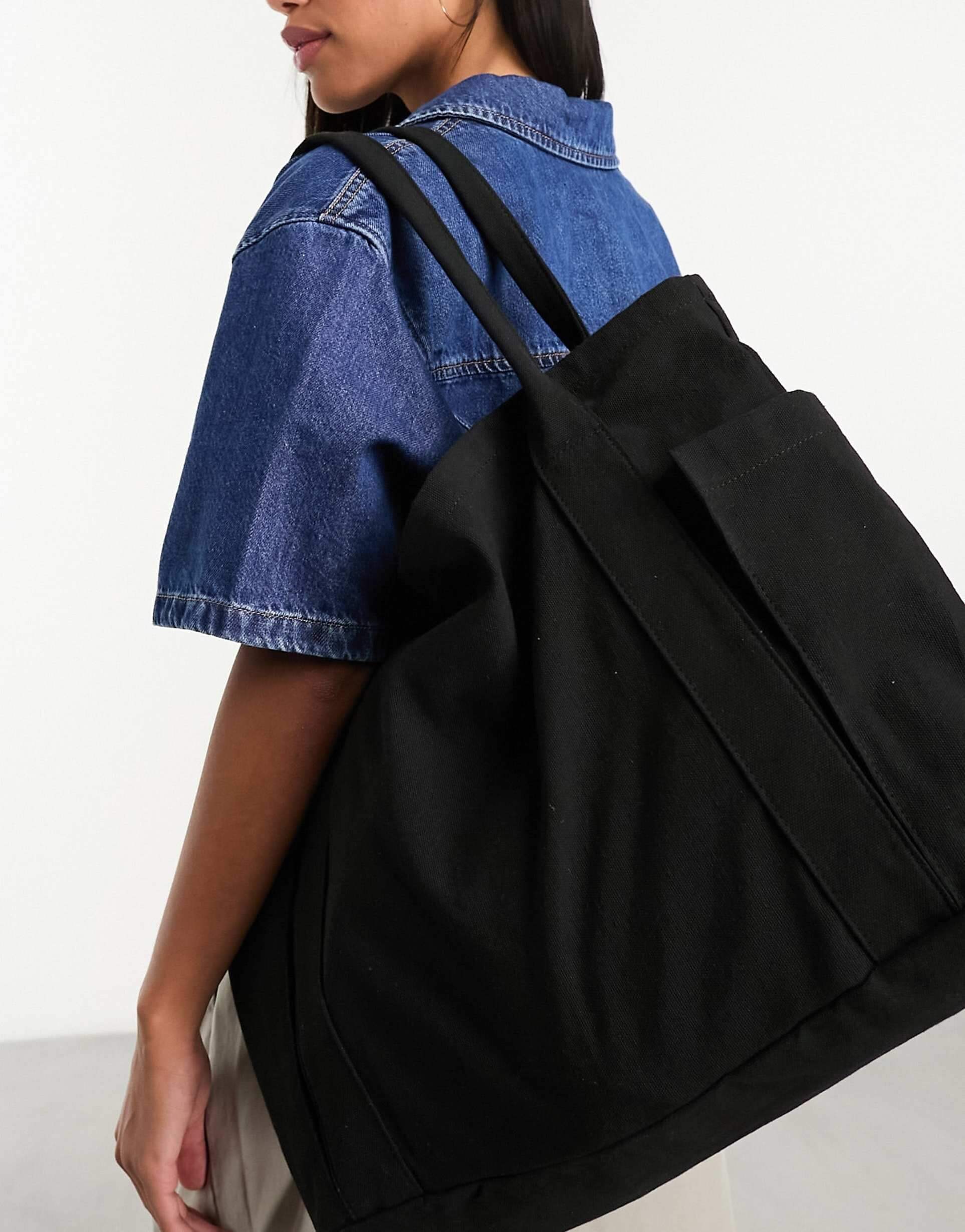 Model wearing ASOS Design Oversized Heavyweight Canvas Tote Bag in black, paired with a denim jacket