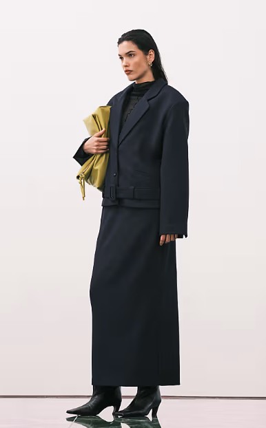 Side view of model wearing ASOS Design Tailored Belted Hem Blazer Midi Pencil Skirt in navy colour styled with boots