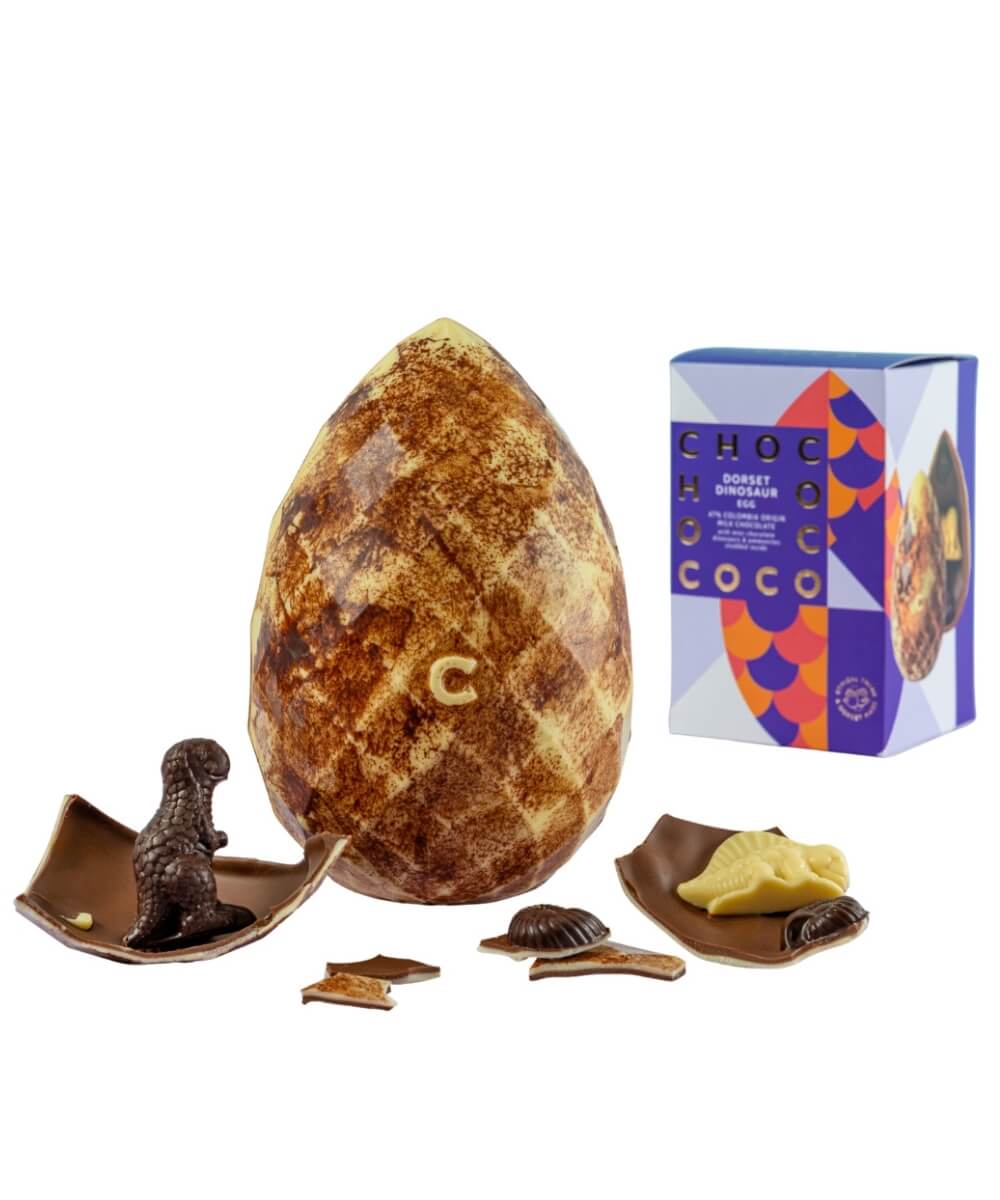Chococo giant milk chocolate Dorset dinosaur egg with speckled shell, broken pieces, and chocolate dinosaur inside alongside branded packaging