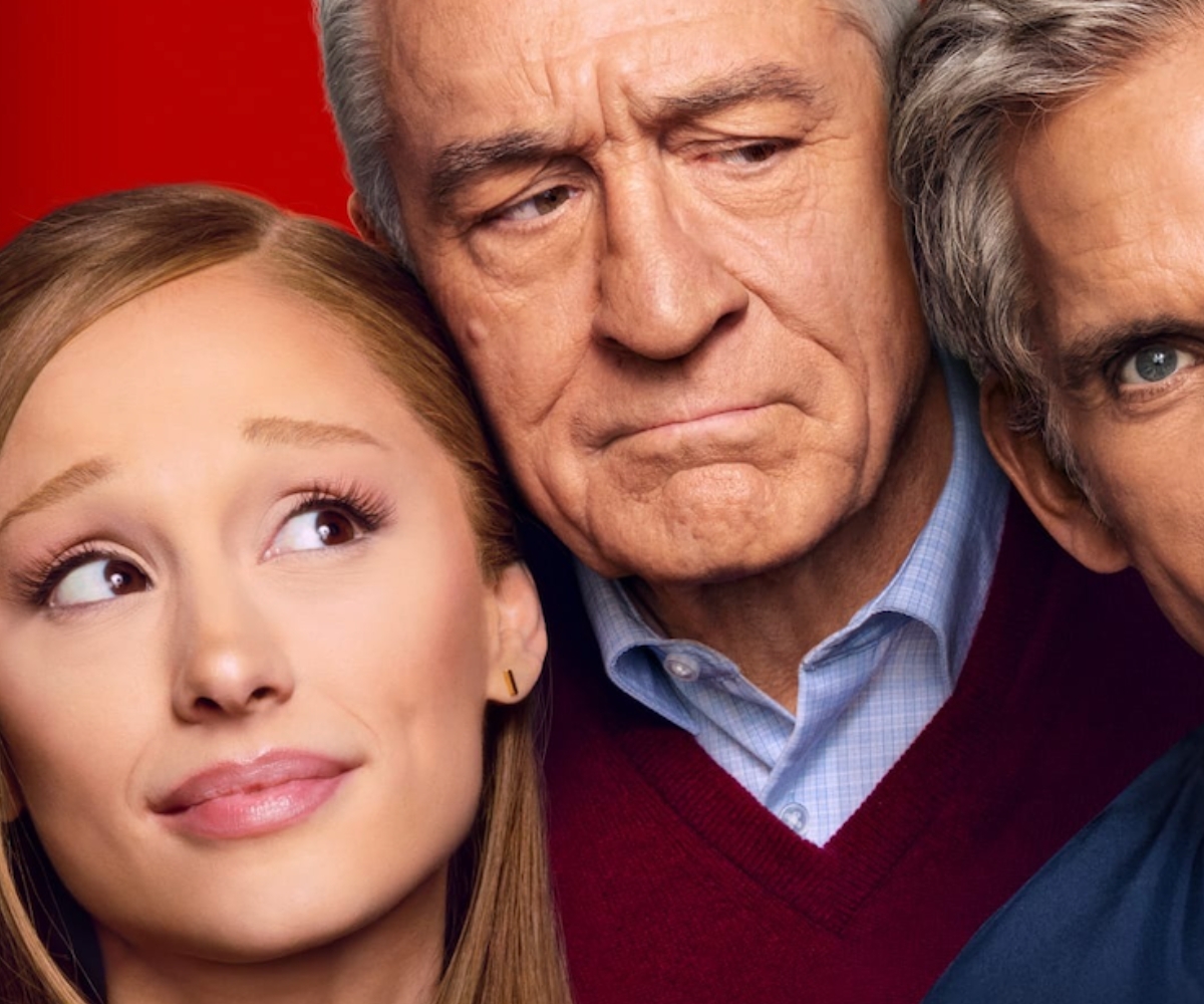 Ariana Grande in the foreground with Robert De Niro in the centre and Ben Stiller partially visible on the right against a red background. New Meet The Fockers Movie - Focker-In-Law