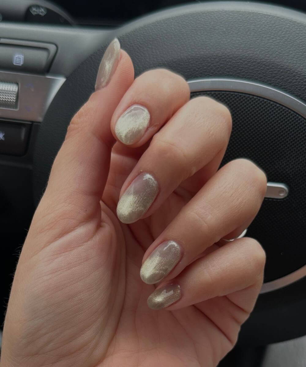 Short rounded nails with gold cat eye effect on a glossy base, featuring a magnetic shimmer finish for a modern spring manicure