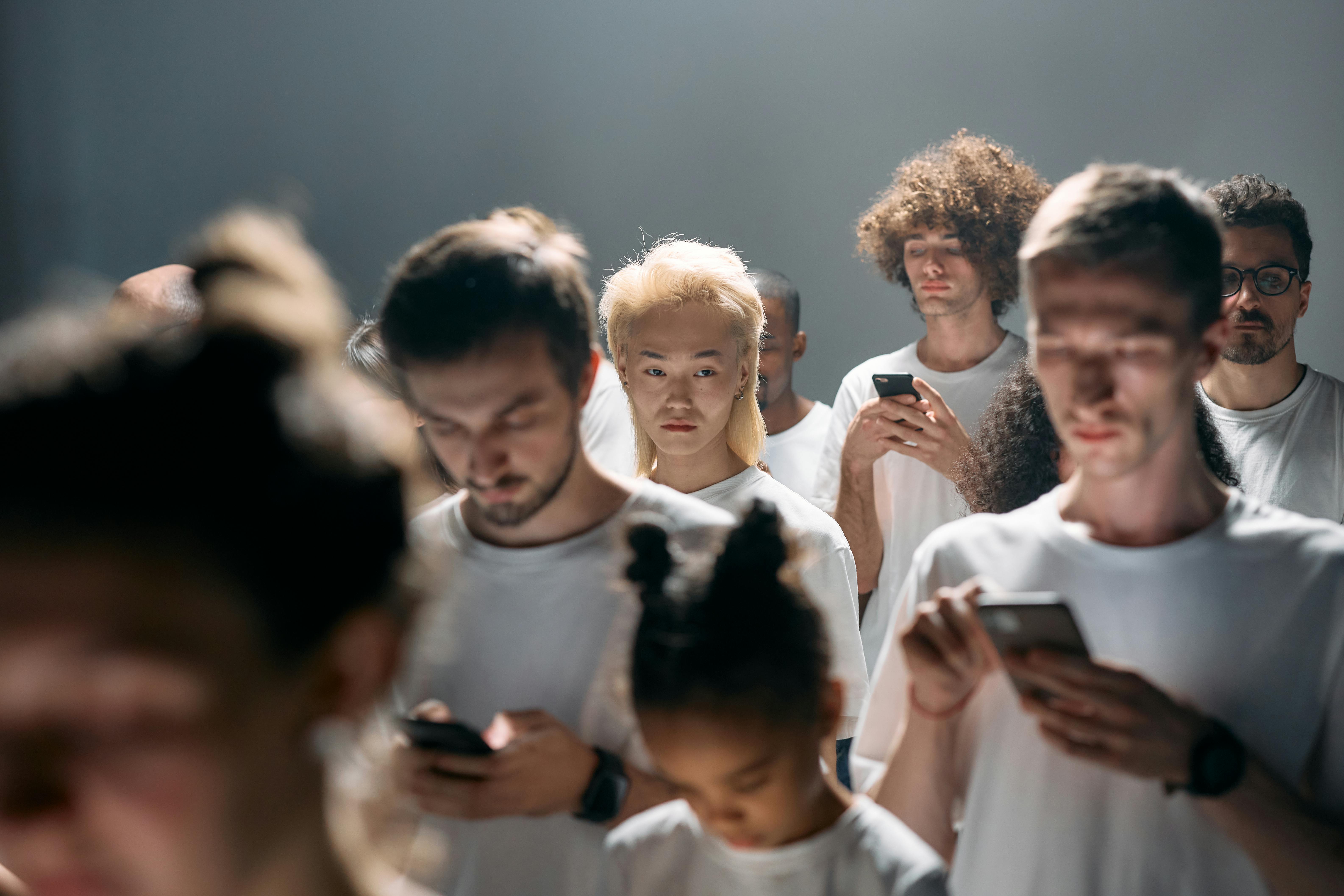 Group of people dressed in white standing and looking down at their phones - Inside the Manosphere