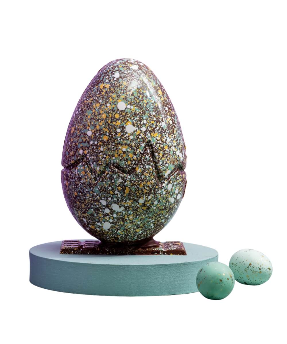 Hazel Mountain Chocolate pistachio and raspberry 42% milk chocolate Easter egg with colourful speckled hand-painted shell on display stand