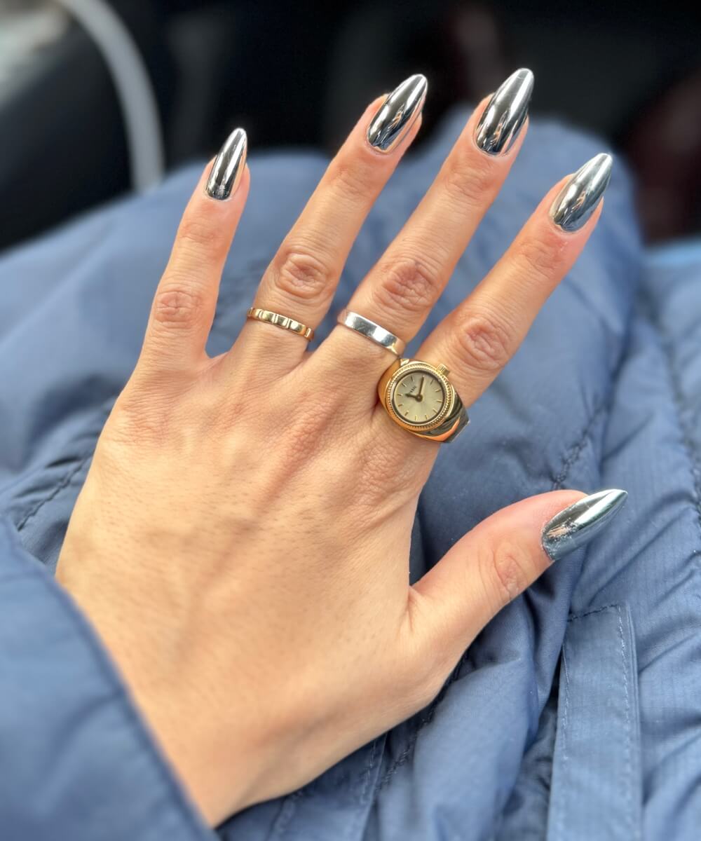 Close-up of almond-shaped nails with reflective silver chrome finish and high-shine mirror effect, creating a bold and modern nail look