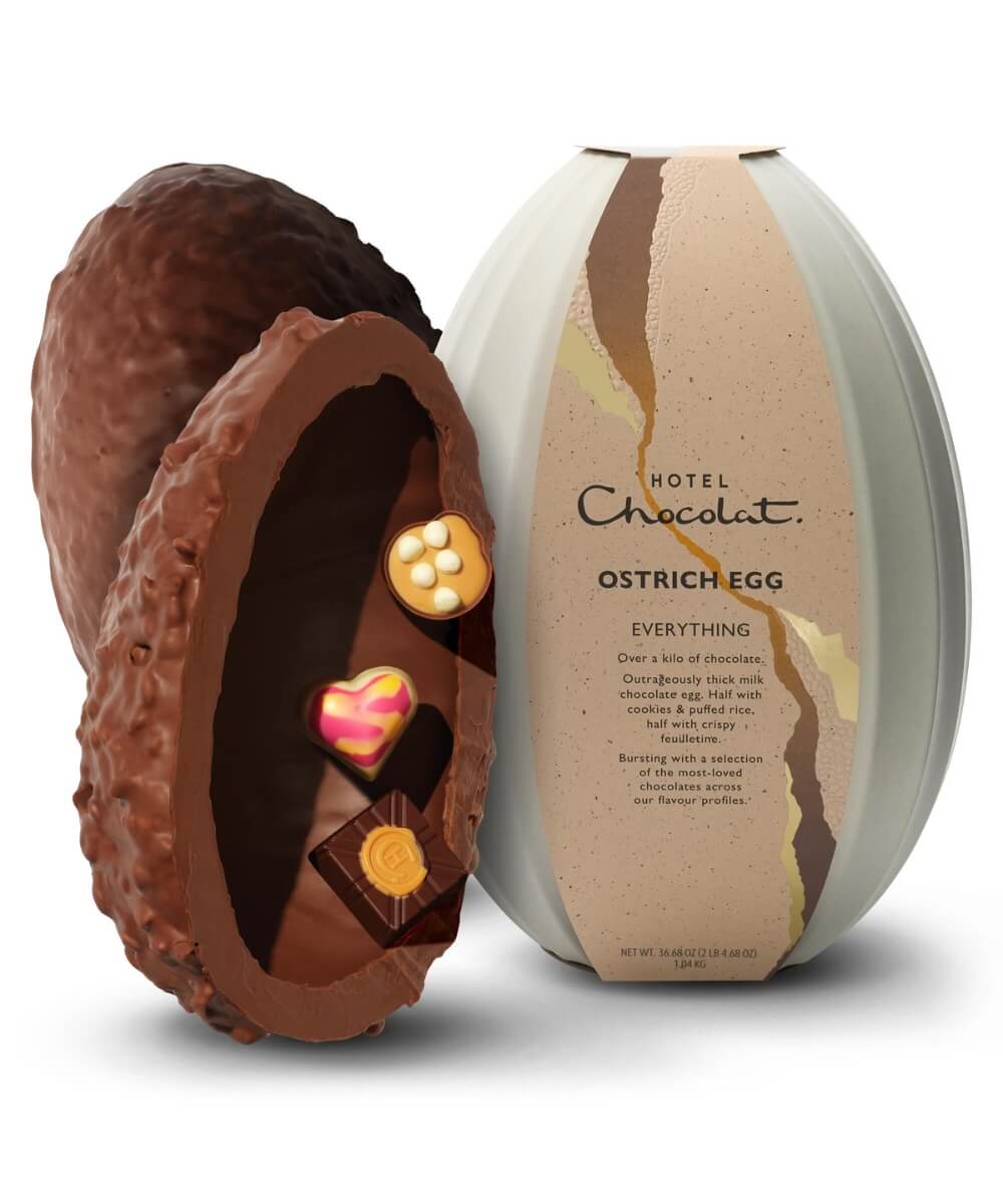 Hotel Chocolat Everything Ostrich Easter egg with thick milk chocolate shell and assorted chocolates inside beside grey cacao pod gift packaging