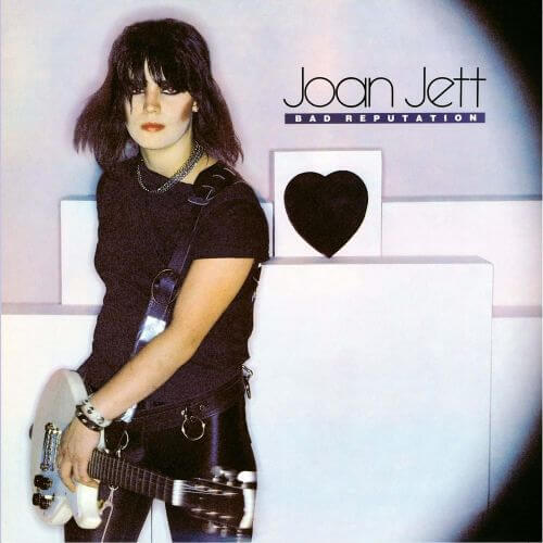 Joan Jett on the Bad Reputation album cover, holding a white electric guitar beside a black heart graphic, representing one of the best girl power songs in rock history.