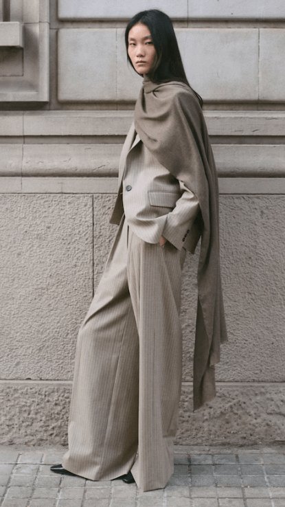 Model wearing the Mango Wool-blend suit trousers in medium brown, featuring a relaxed wide-leg fit with subtle pinstripes and a tailored waistband