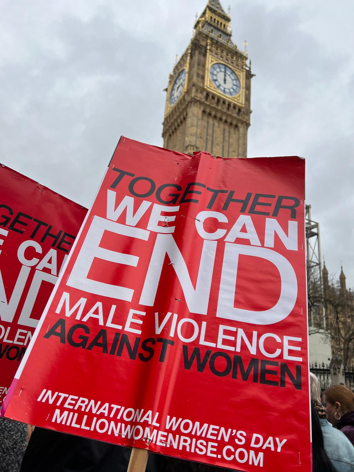 Women's protest London sign reading 'Together we can end male violence against women' during the Million Women Rise March in London with Big Ben visible behind women protesters