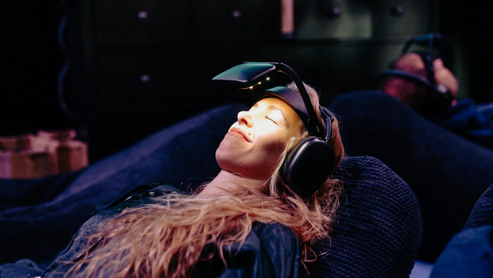 Woman using a NeuroVIZR brain-wellness device with light and sound stimulation, part of a longevity and biohacking wellbeing experience.