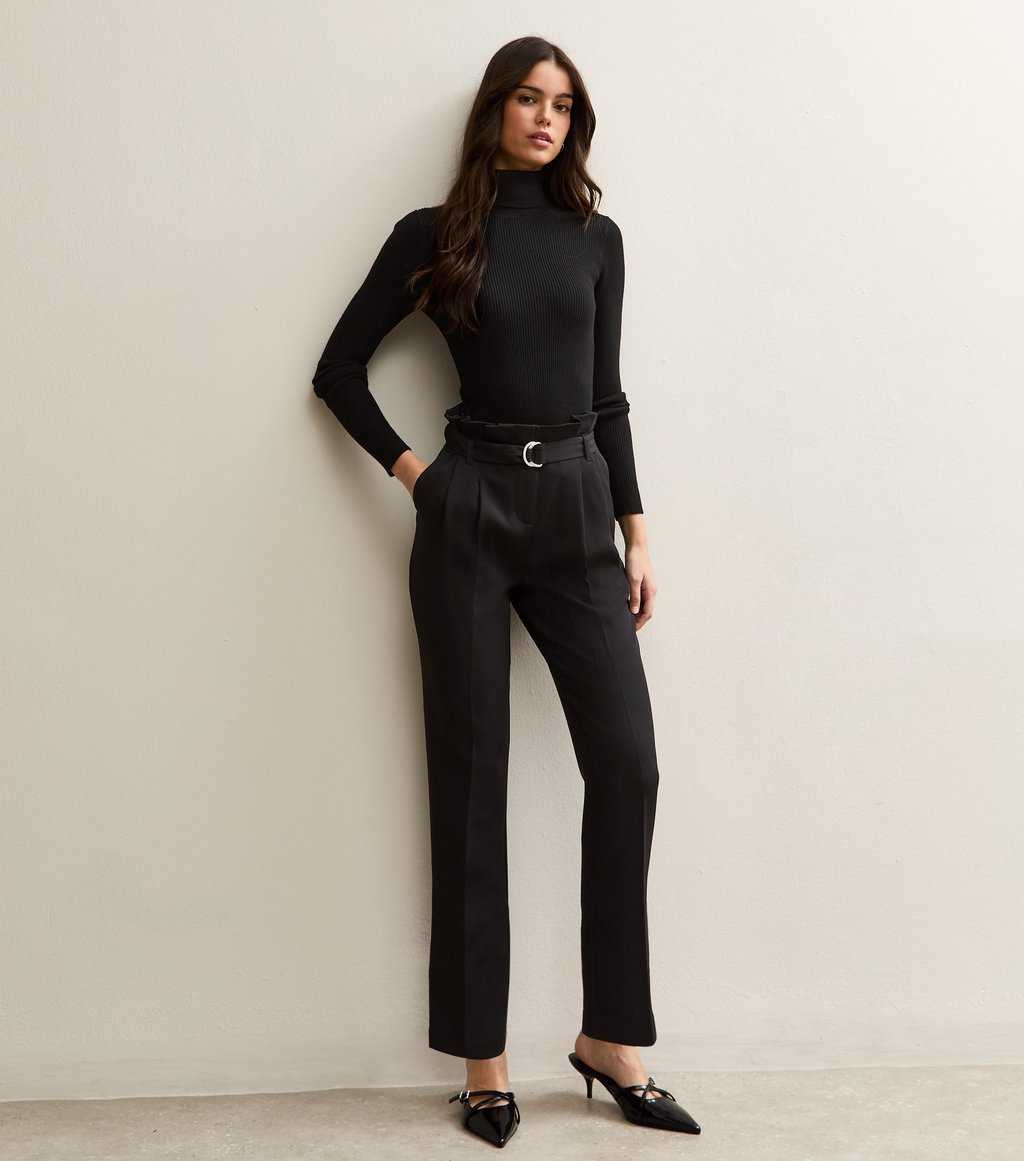 Model wearing New Look black belted paperbag waist trousers, paired with a black turtleneck and heels