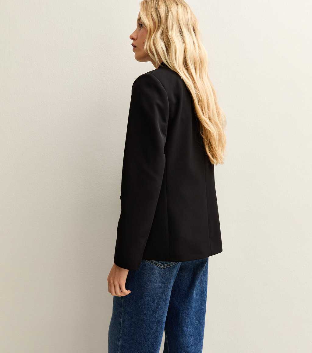 Side view of a model wearing New Look single-breasted black blazer over a white blouse and blue jeans