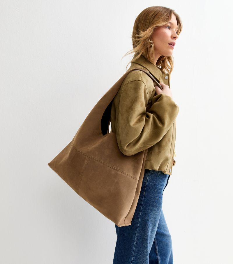 Woman carrying New Look camel oversized faux suede panel tote bag with relaxed slouchy shape and shoulder strap.