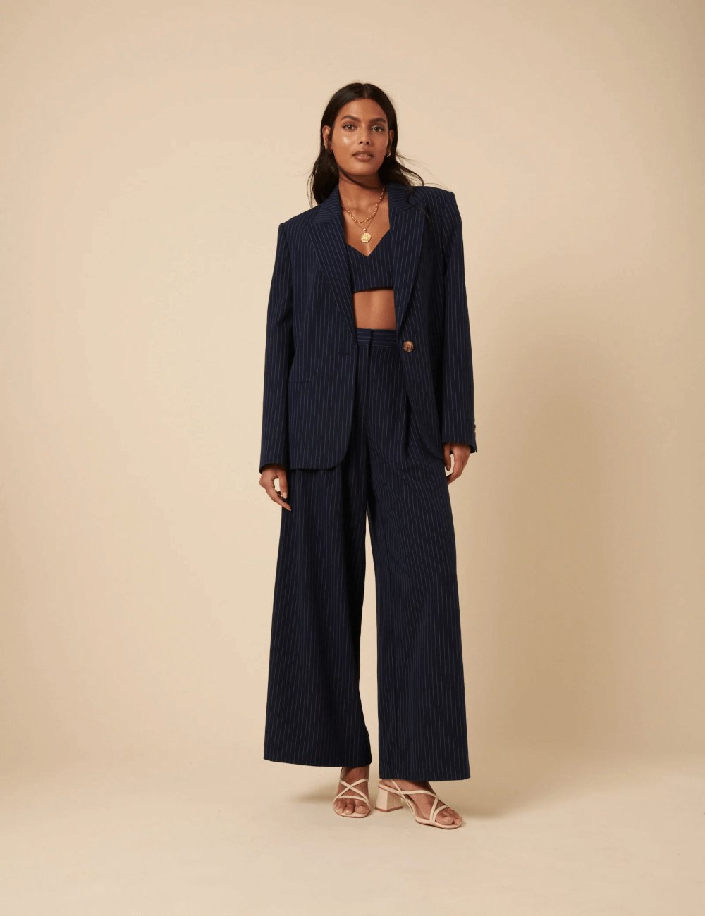 Model wearing Nobody’s Child Poppy Delevingne Navy Pinstripe Cara Blazer, a tailored blazer with brown buttons