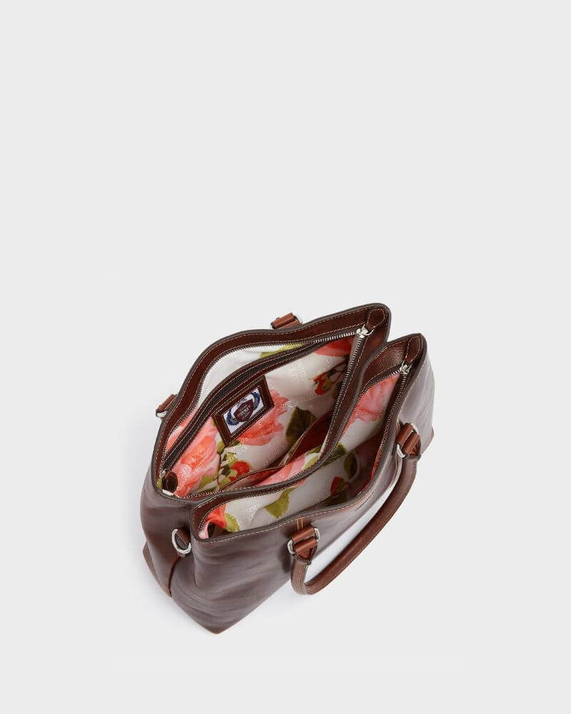 Interior view of the chestnut Osprey London The Madden leather shoulder bag showing multiple compartments, zip pockets and floral lining. The organised layout is designed to securely hold daily essentials and work items.