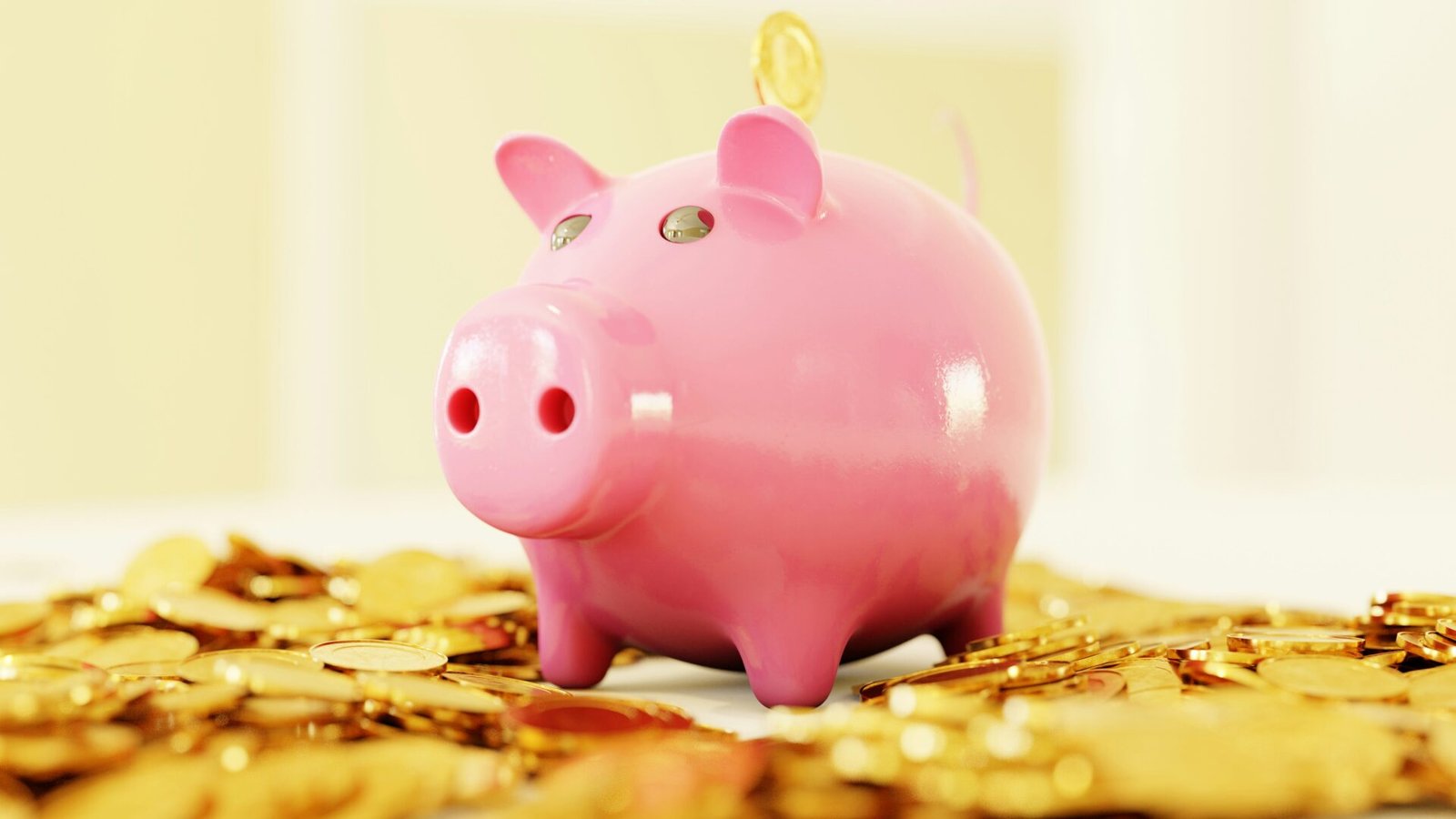 A pink piggy bank surrounded by shiny gold coins, symbolising savings and financial growth - best budgeting app