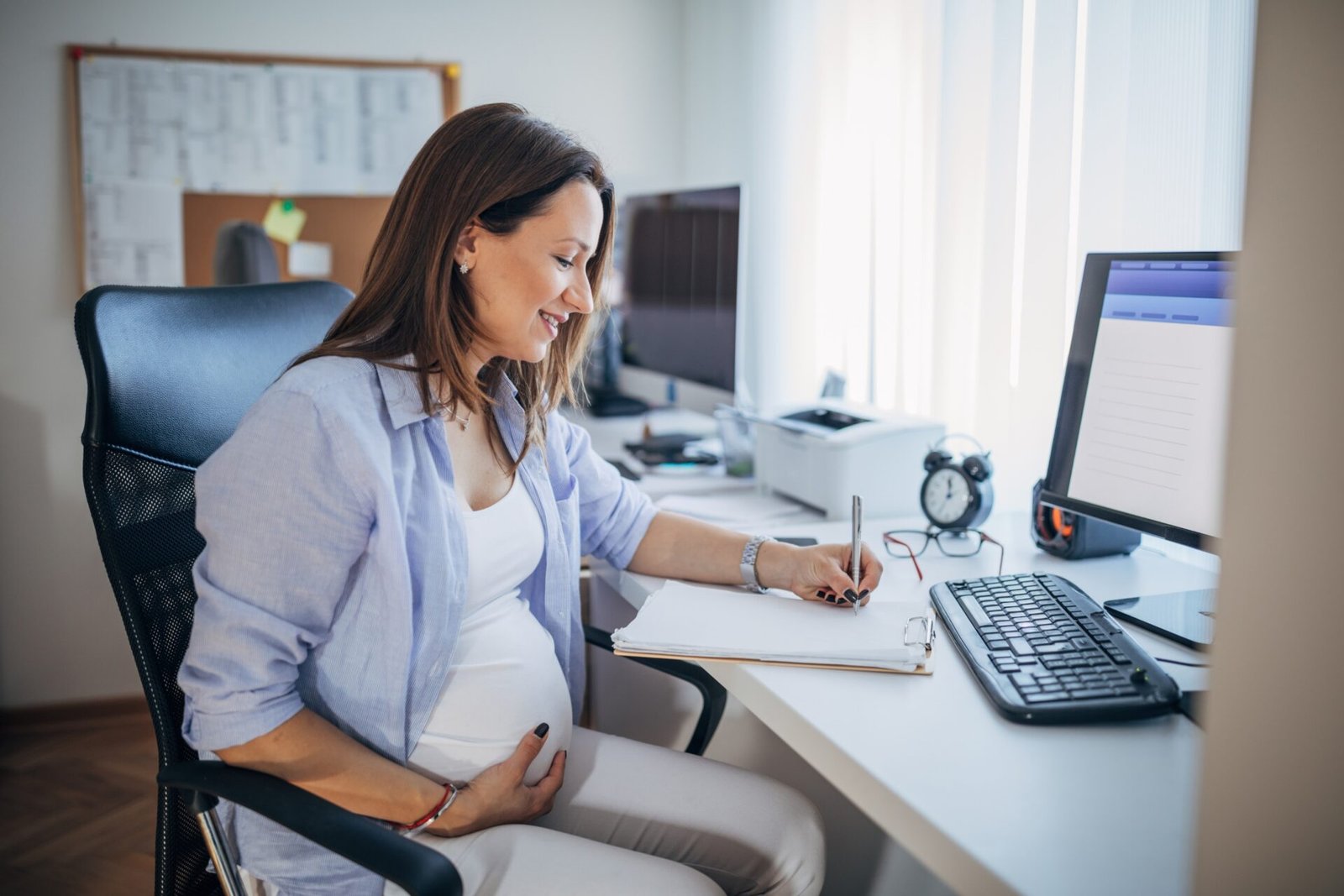 Pregnant woman working at a desk in an office, illustrating pregnancy and maternity rights at work in the UK