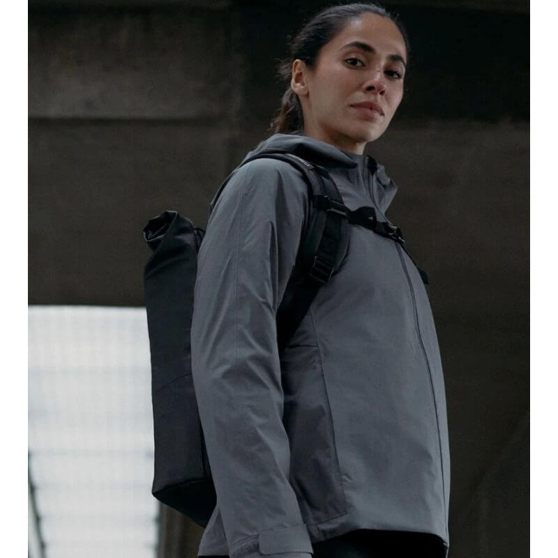 Model wearing a grey jacket carrying a black Stubble & Co roll-top backpack.
