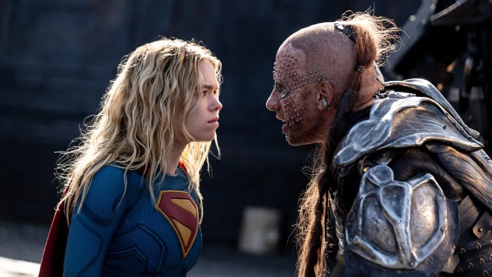 Milly Alcock as Kara Zor-El confronts Krem of the Yellow Hills in a tense scene from Supergirl (2026), with Supergirl wearing her blue and red suit as the two characters face each other before battle.
