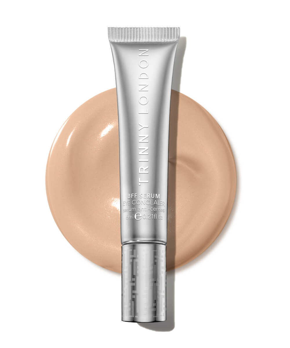 Trinny London BFF Eye Serum Concealer tube beside a creamy beige swatch on a white background