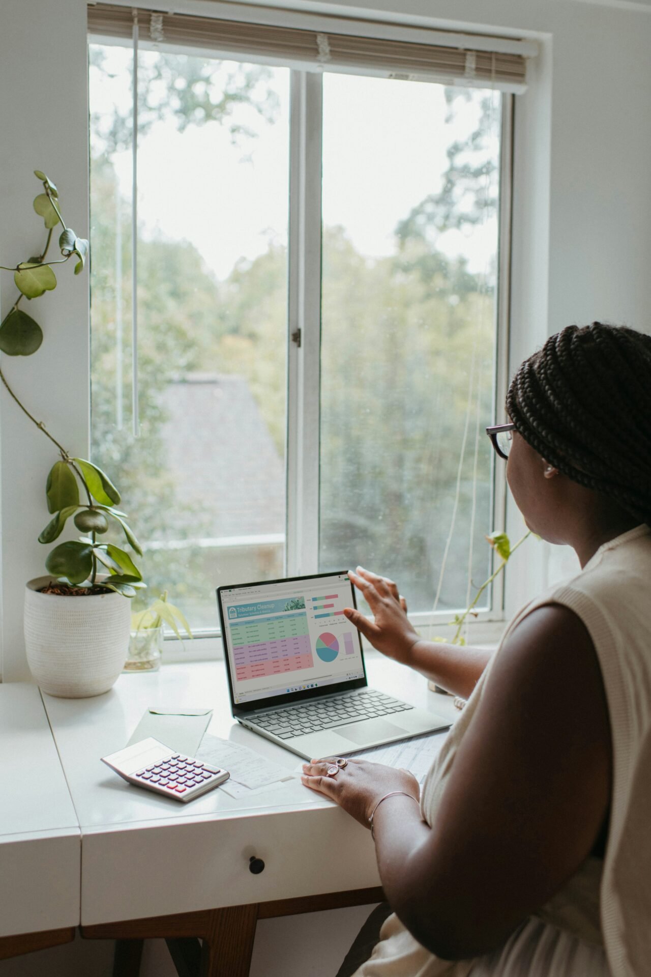 A woman seated at a desk, working on a budget with a calendar visible beside her - best budgeting apps for women