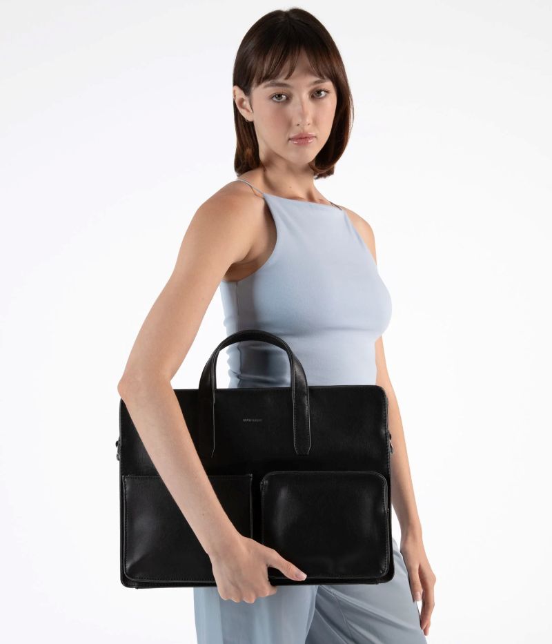 Matt & Nat Soren vintage black vegan leather briefcase with structured silhouette, front compartment and top handles, carried by model.