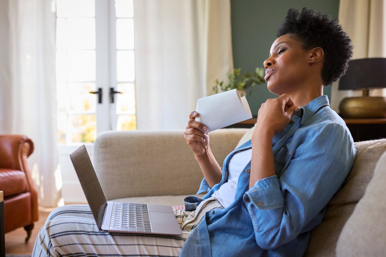 Woman experiencing menopause symptoms while working on a laptop, illustrating menopause rights and support in the workplace