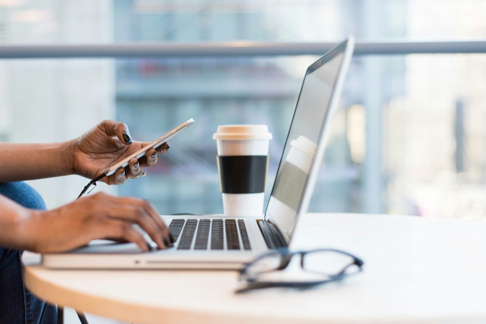 Female founder seated at a table, working on a laptop with a cup of coffee beside her
