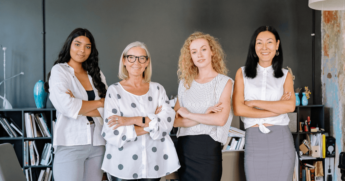 Four working women in an office representing workplace support for working mothers experiencing perimenopause.